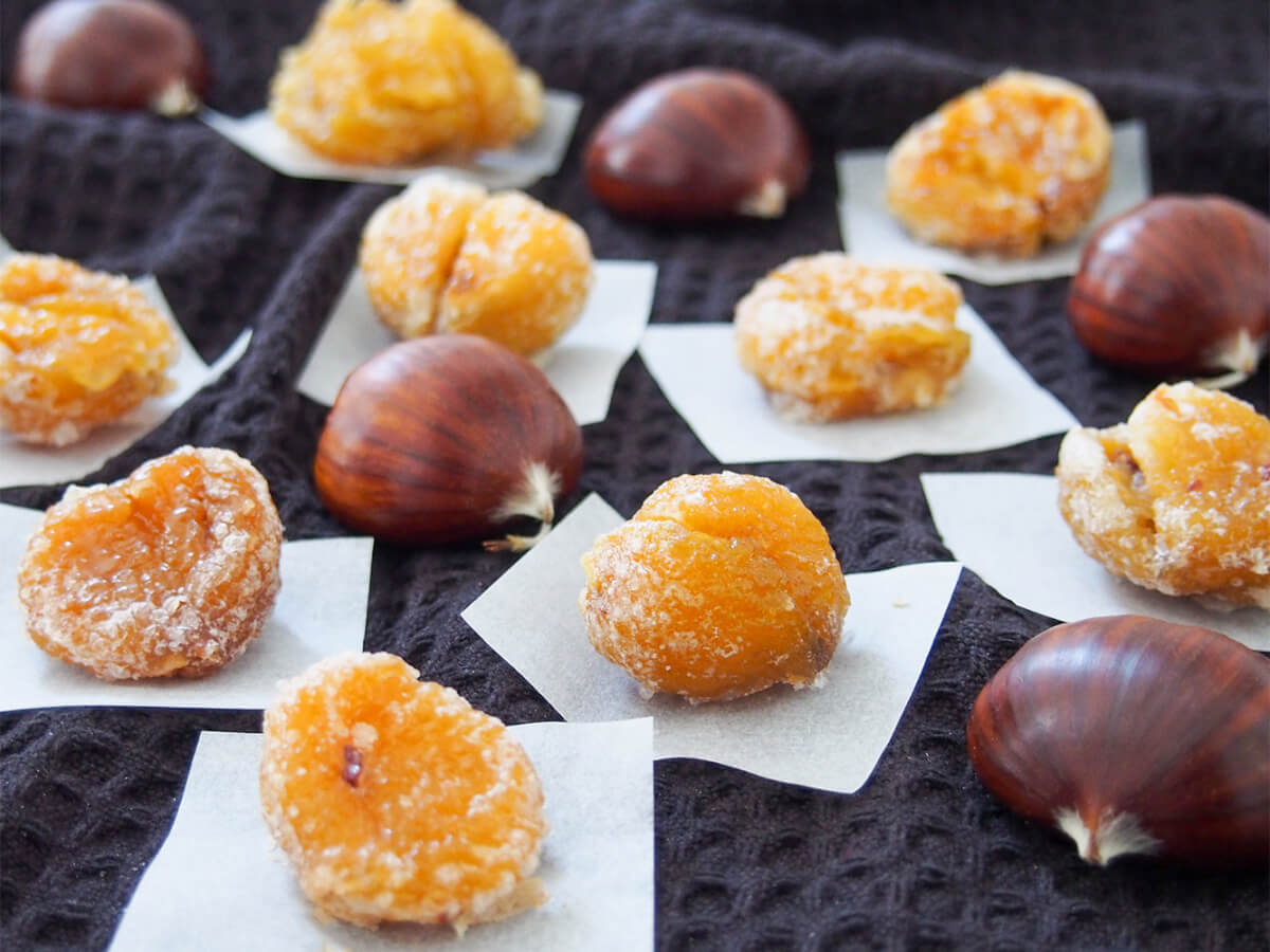 Biting into a marron glacé is such a wonderful treat that I will never say no to. These candied chestnuts are sweet, tender and nutty all in one. While they take some patience to make over a few days, they are not all that difficult. And you'll soon discover, entirely worthwhile. Marron glacé (candied chestnuts) on paper with whole chestnuts in between
