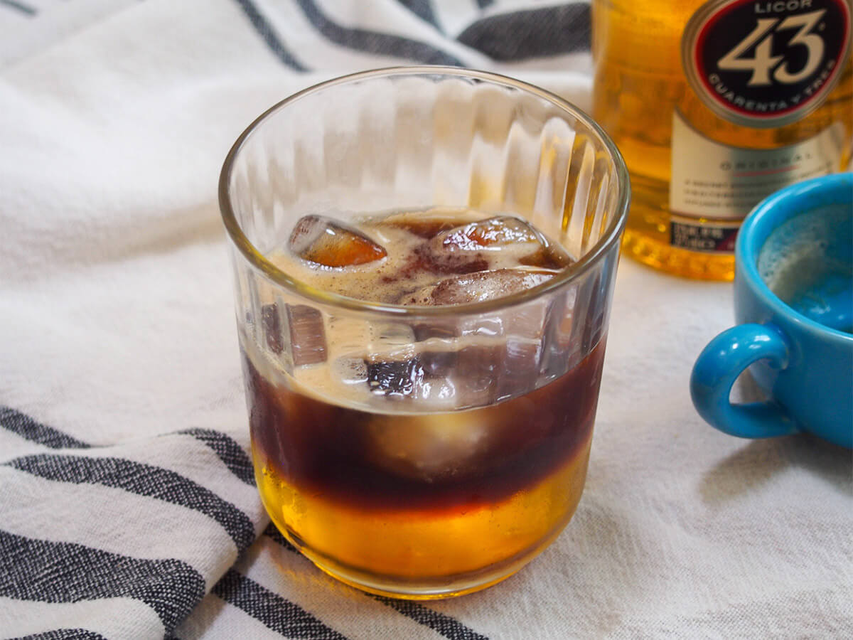 This Mexican carajillo is a super simple, yet complex-tasting coffee cocktail, using the liqueur Licor 43. You enjoy it chilled, over ice, typically as an after dinner drink though it would be great alongside brunch, too. Delicious any time. Mexican carajillo coffee cocktail with bottle of licor 43 behind
