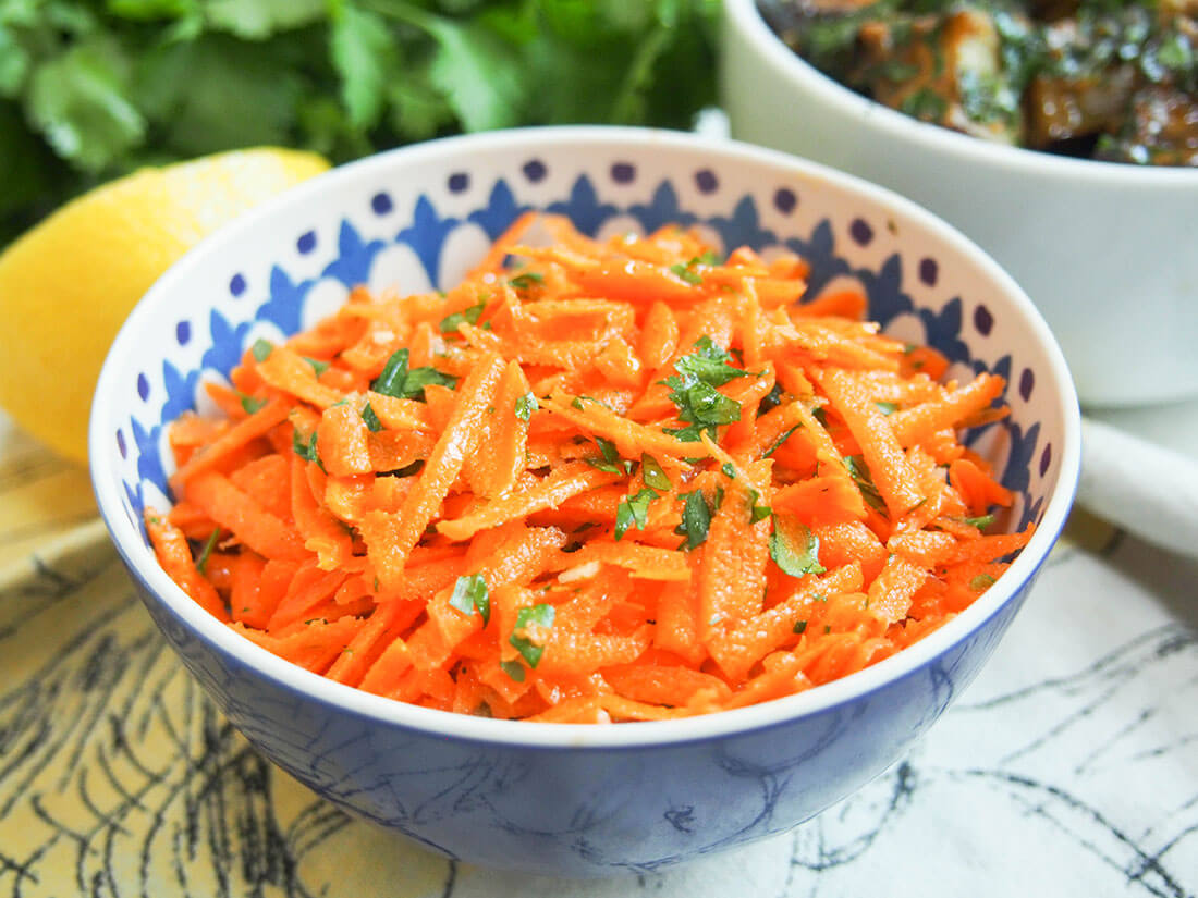 This Moroccan raw carrot salad takes only a few minutes to make, has a short list of ingredients and is packed with flavor. Moroccan raw carrot salad with eggplant salad, lemon and cilantro behind