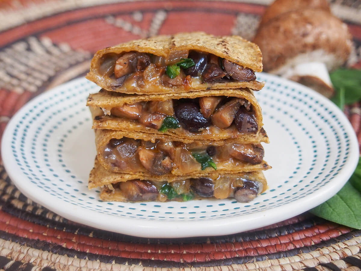 llas but they're still so easy to make and packed with flavor. A delicious snack or light lunch. stack of pieces of mushroom quesadilla with mushroom behind plate