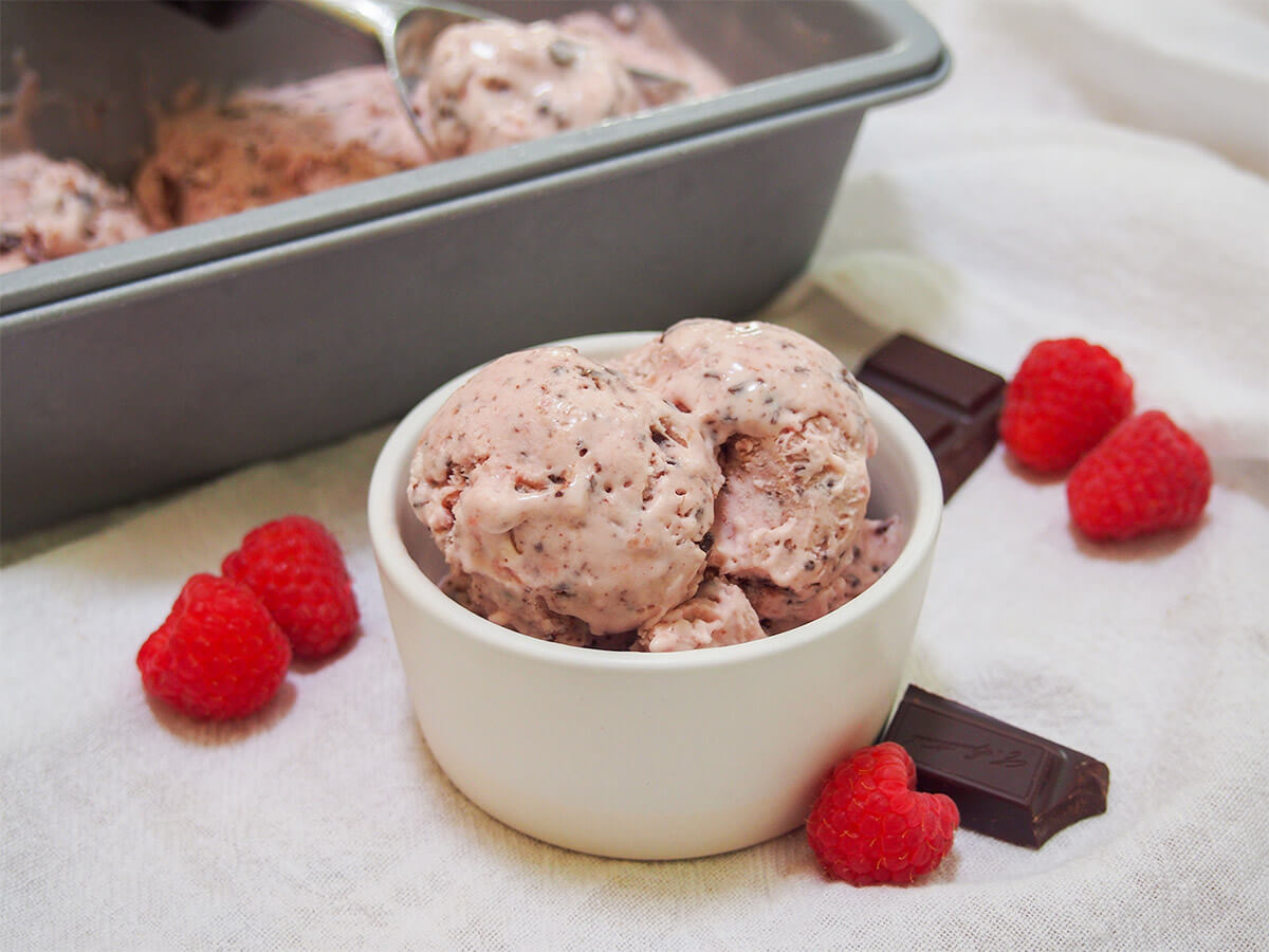 This no churn raspberry chocolate chip ice cream is a delicious mix of sweet creaminess, gently tart fruit flavor and bursts of crunchy rich chocolate. So tasty, easy to make and the perfect way to cool down. no churn raspberry chocolate chip ice cream in dish with container with more behind