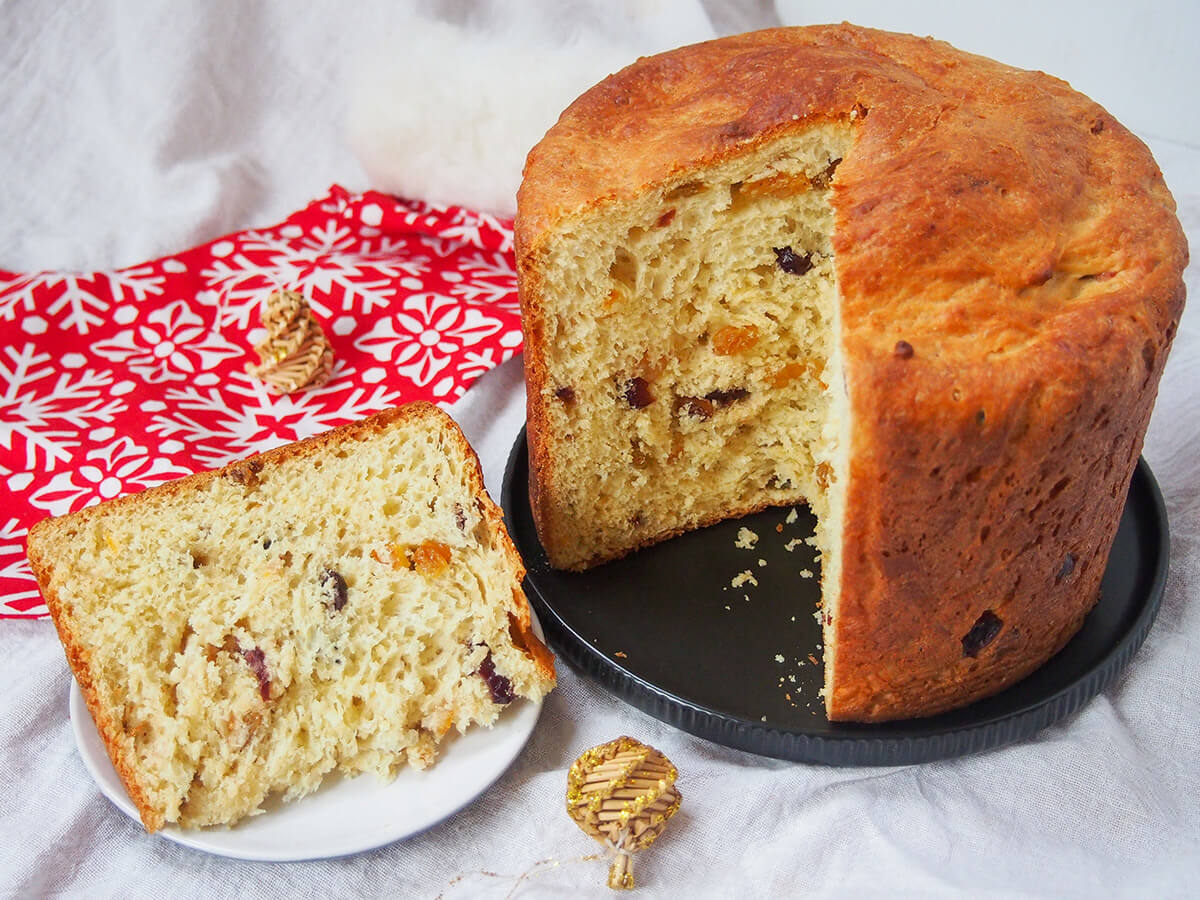 Panettone is a slightly sweet Italian bread, studded with fruit, that's common over the festive season, both for gifting and serving guests. It has a lovely gently citrus flavor and light texture - so easy to enjoy. slice of panettone on small plate with rest of loaf on plate to side