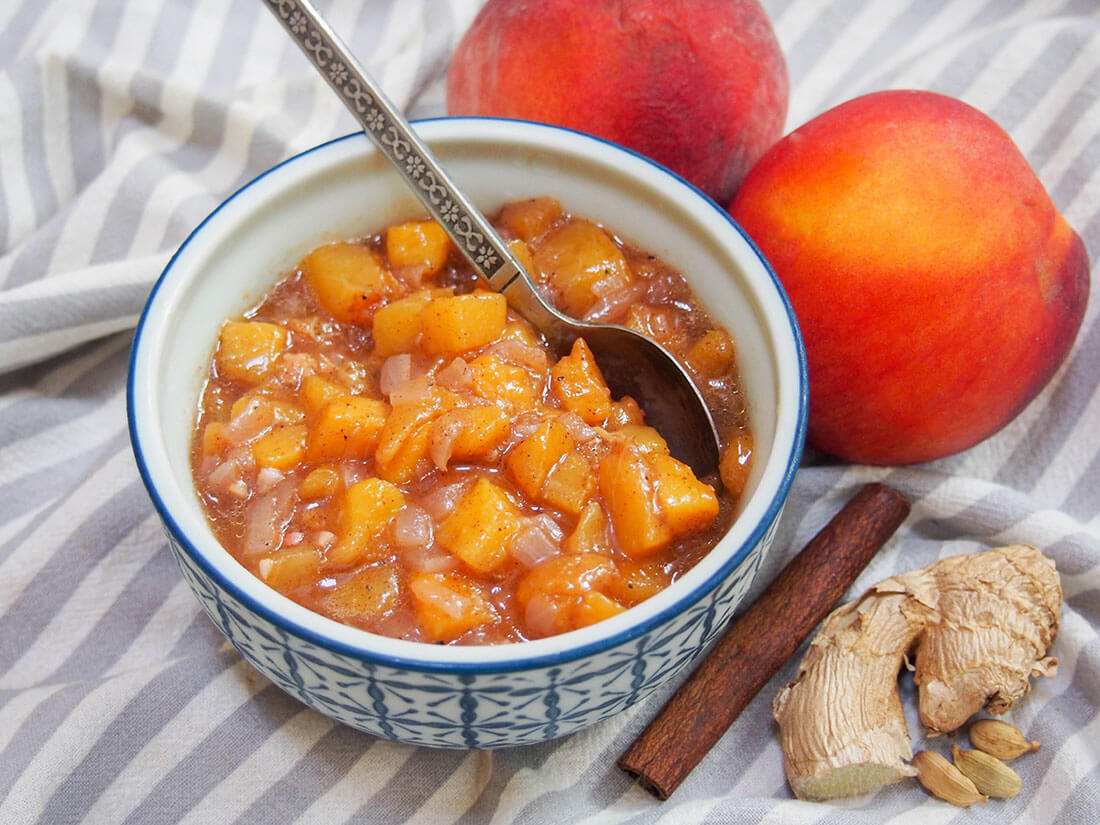 This peach chutney takes mere minutes to make, with a delicious balance of fruitiness and warm spices. peach chutney in bowl with peach and spices to side
