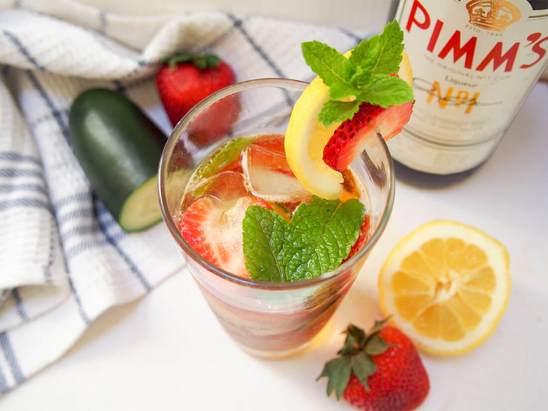 A Pimm's cup cocktail (Pimm's and lemonade) is such a classic, easy British cocktail. It's light, fresh and perfect for summer barbecues, picnics or any excuse you can find. Pimm's cup cocktail with bottle and garnishes to side