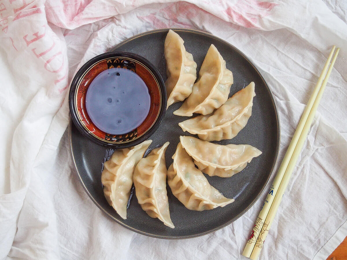 Pork and cabbage dumplings are a traditional dish eaten for Chinese New Year, but these dumplings are so delicious you'll want to have them more often! pork and cabbage dumplings on plate with chopsticks to side of plate