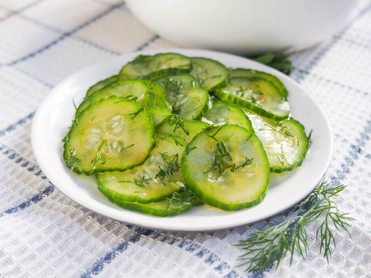 Pressgurka are Swedish pressed cucumbers or quick pickles. They are so easy to make and a delicious side to meatballs, gravlax, sandwiches and more. plate of pressgurka Swedish cucumber with sprig of dill to side