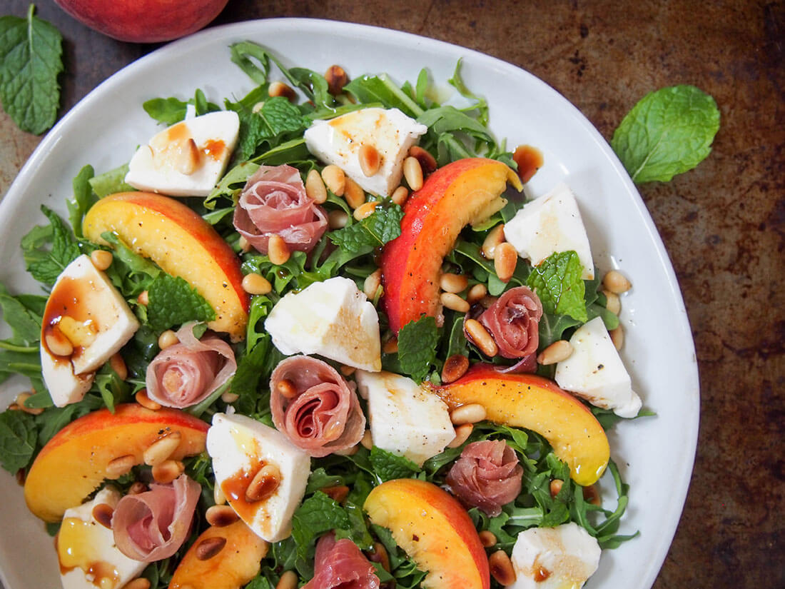 This prosciutto salad with peach and mozzarella is an elegant and delicious way to enjoy the fantastic flavors of summer. Better yet, it's easy to make. partial overhead shot of plate of prosciutto salad with peach and mozzarella