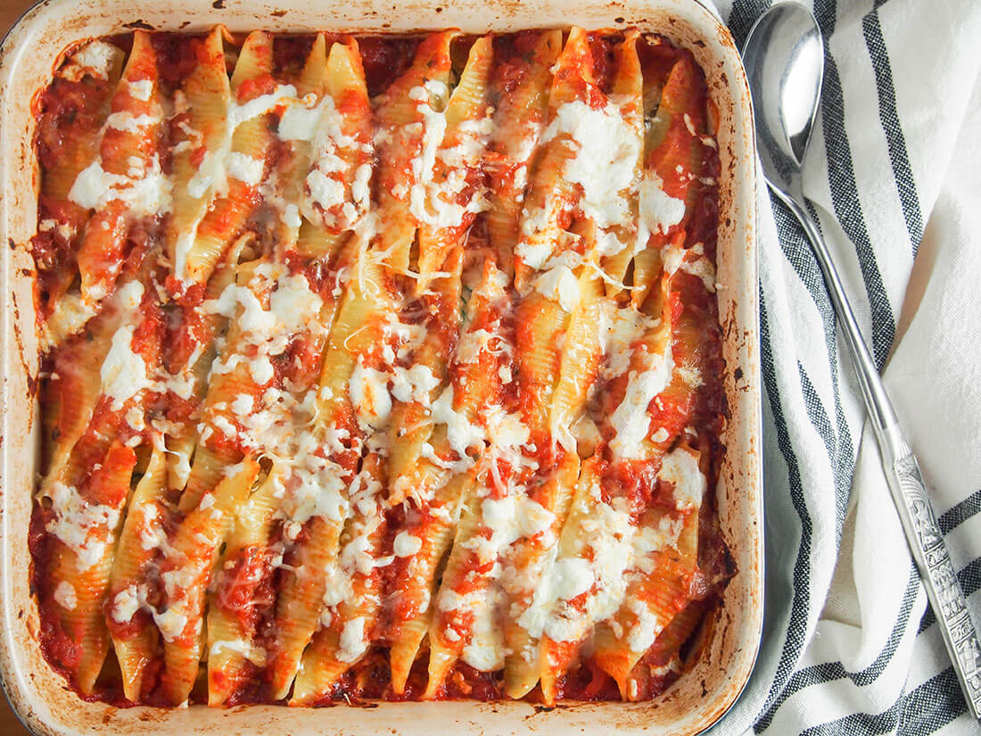Give leftover pulled pork a new lease of life in another wonderfully comforting dish. These pulled pork stuffed shells are a delicious combination of flavorful pork, cheesy goodness, all nestled in tomato sauce. So good! dish of pulled pork stuffed shells with serving spoon to side