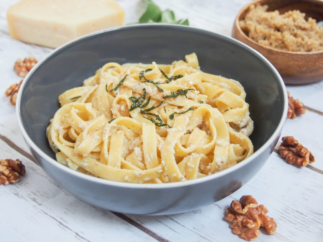 This pumpkin pasta is a delicious way to enjoy a touch of fall in homemade pasta with real pumpkin in the dough. If you're a pasta fan, you'll be blown away at how good it can taste. pumpkin pasta with walnut sauce mixed through and dish with additional sauce behind