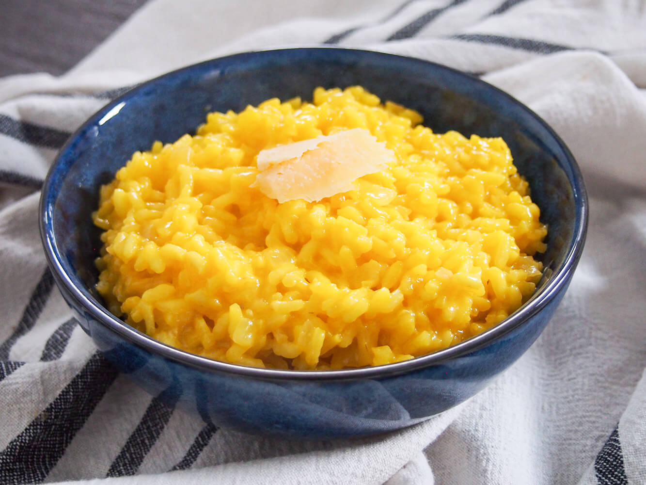 bowl of saffron risotto - a wonderfully easy and delicious Italian rice dish blue bowl filled with saffron risotto