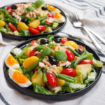 plate of salade Nicoise with second plate of salad behind