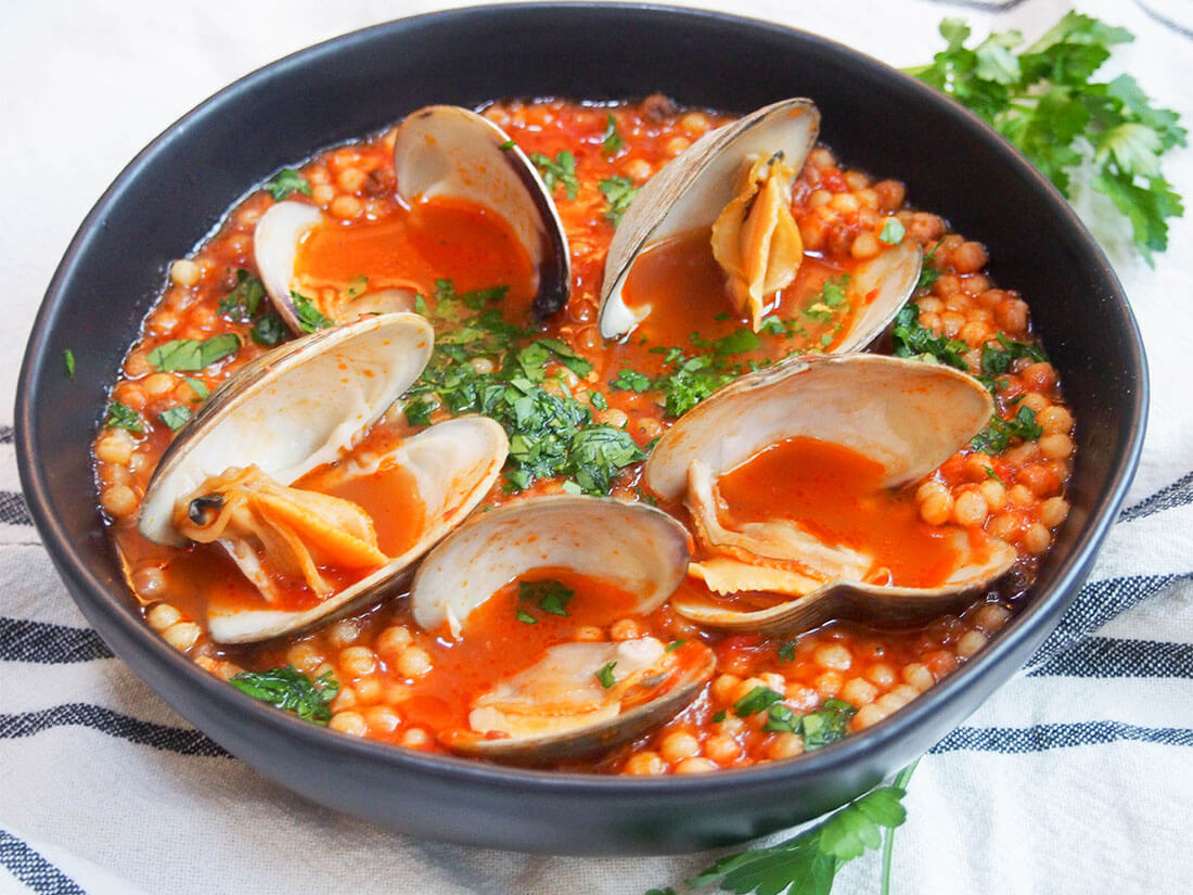 This Sardinian fregola with clams only uses a few ingredients but has such a wonderful flavor. It's easy to make, comforting but not too heavy, and a delicious meal any night of the week. bowl of Sardinian fregola with clams