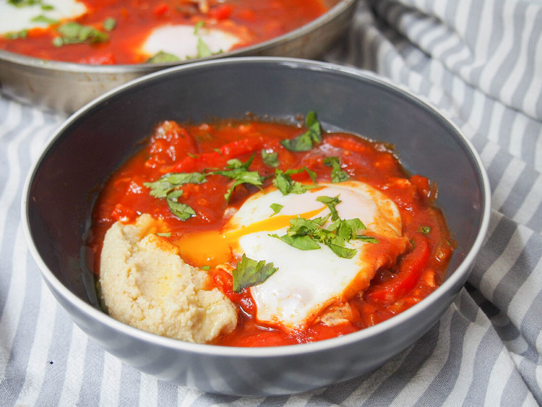 What happens when two already tasty Mediterranean favorites collide? You get one deliciously comforting dish! Shakshuka hummus is perfect for brunch, lunch or anytime. shakshuka hummus in a bowl with egg yolk running into hummus