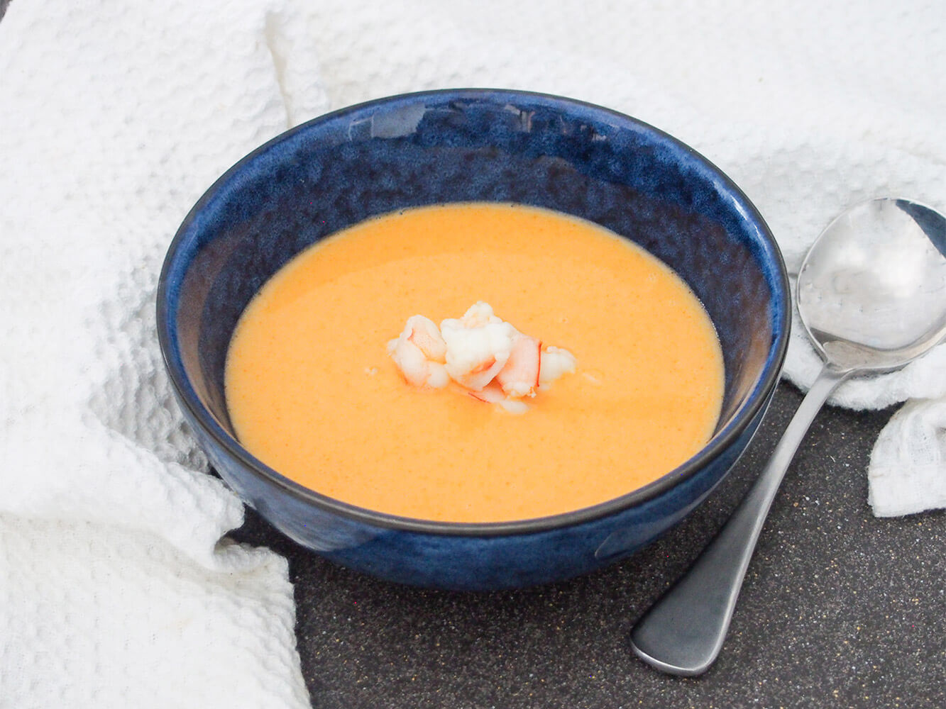Shrimp bisque is a luscious, smooth and flavorful chowder-like soup. It has an elegant pink color and tastes so good you'll want to serve it for dinner parties and more. bowl of shrimp bisque with spoon to side