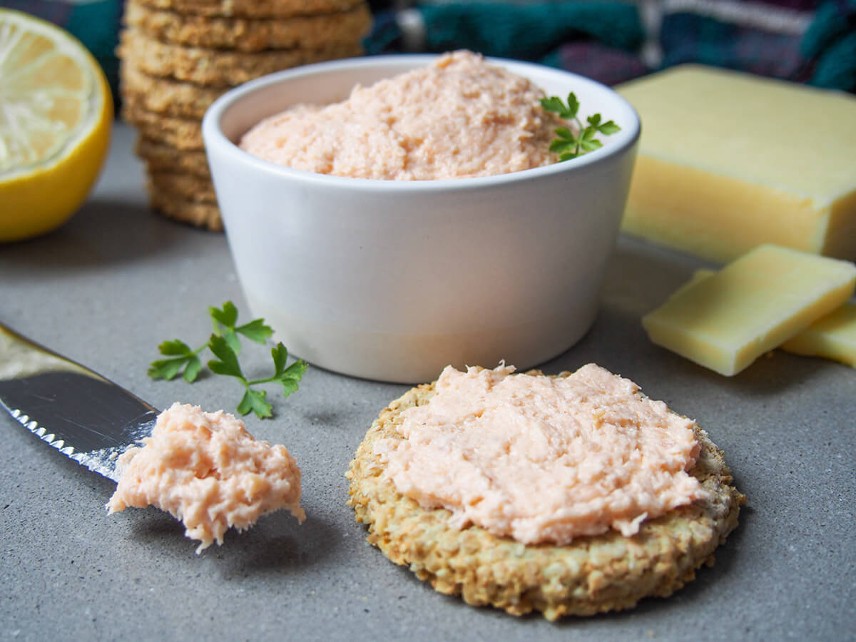 This smoked salmon pate is jam-packed with delicious salmon flavor and really easy to make. It's perfect to top canapes, as part of a cheeseboard or in sandwiches. smoked salmon pate on oatcake and in dish behind