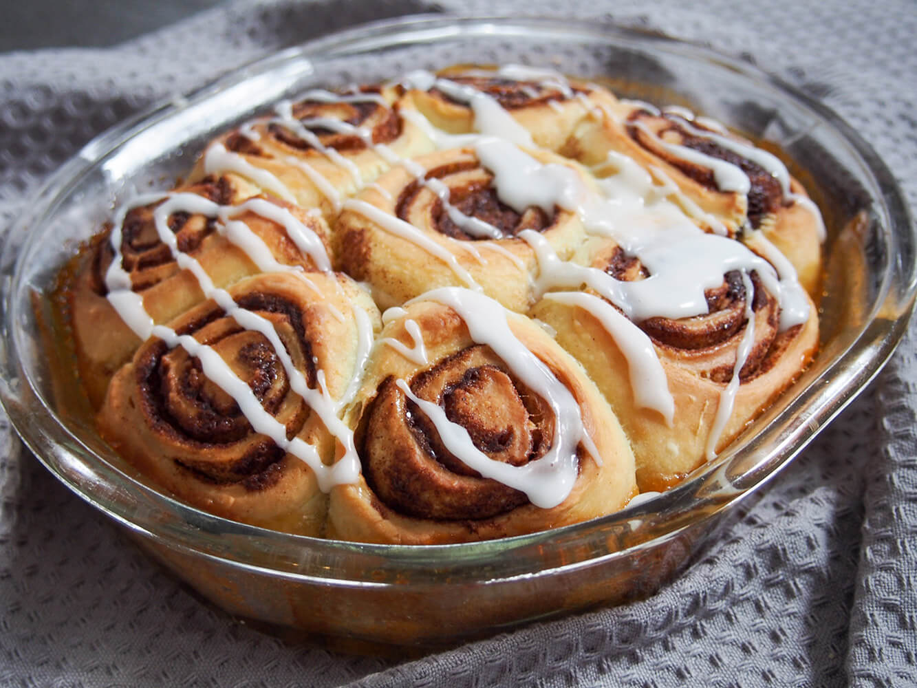 Give your starter a different use in these fluffy sourdough cinnamon rolls. They are packed with delicious flavor and have a wonderful texture. Prepare the night before or the same day as suits. sourdough cinnamon rolls in baking dish decorated with glaze