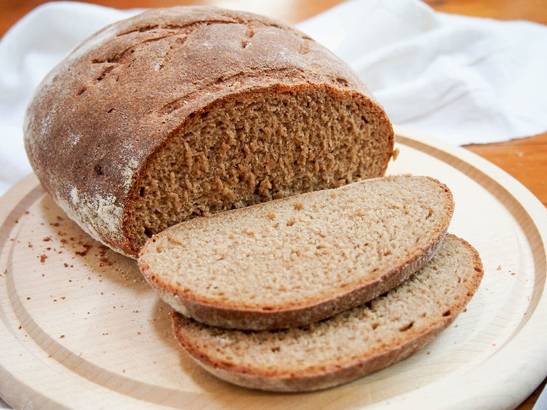 Rye bread comes in many shapes and sizes, and this sourdough rye bread is based on the German style "Mischbrot" using part rye and part wheat. It's a bit lighter than a full-on rye, but packed with wonderful flavor. sourdough rye bread side on with slices in front of rest of loaf