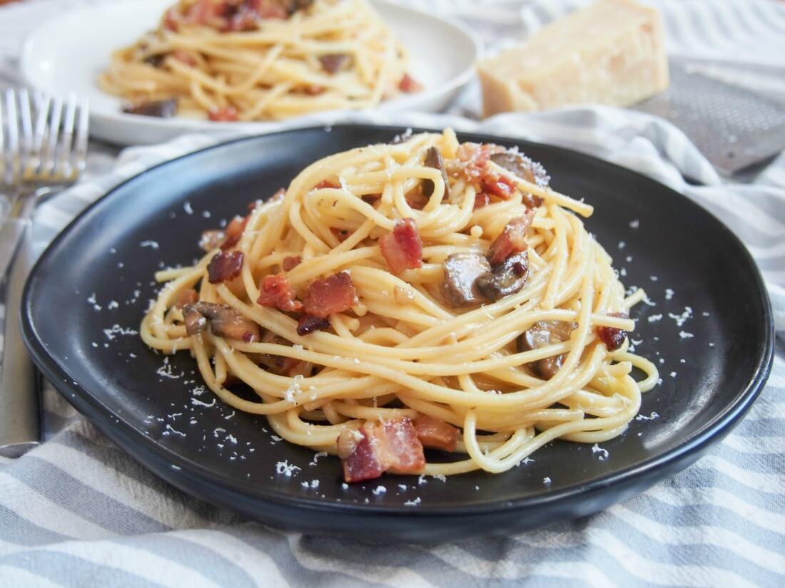 Spaghetti alla carbonara, like many classic Italian pasta dishes, is definitely one of those dishes that makes a few ingredients into something special. This slight twist on the classic is easy and delicious! Spaghetti alla carbonara with mushrooms on plate with forks to side and another plate behind