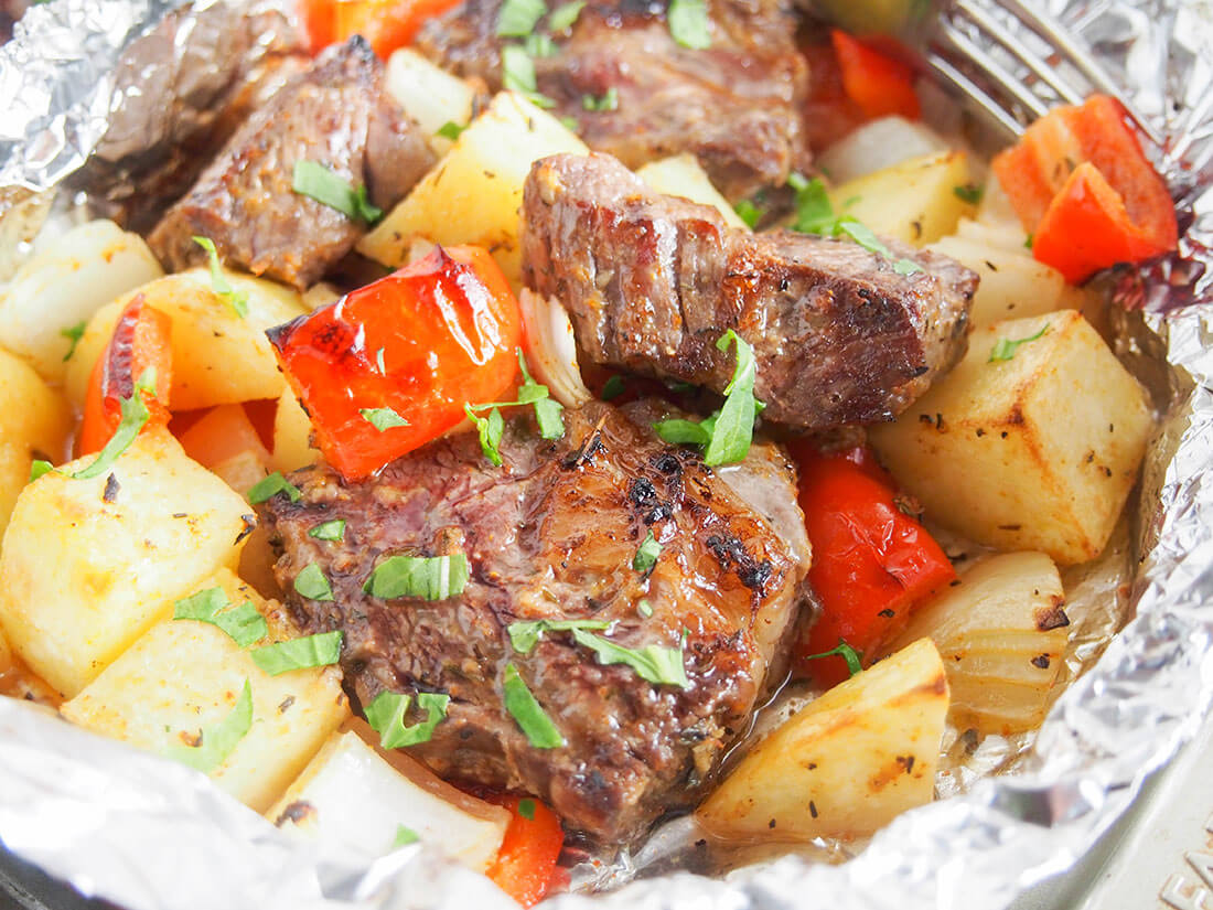 These steak foil packets are easy to prepare, the whole meal all cooked together and with minimal clean up. Flavorful, easy to adapt, it's one to enjoy year round. close up view of steak foil packets with potato and pepper