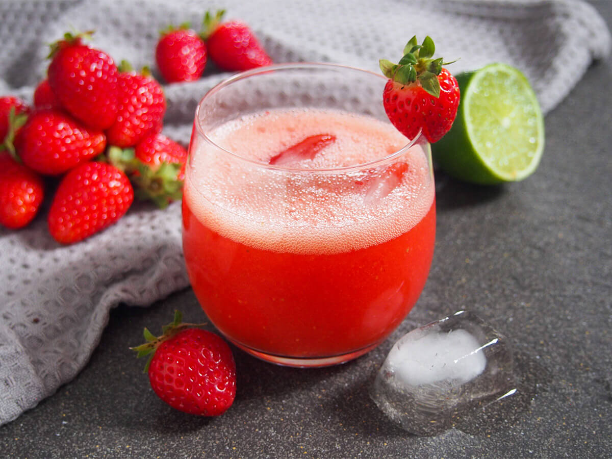 glass of strawberry agua fresca - easy to make and so refreshing glass of strawberry agua fresca with strawberries to one side and half lime to other