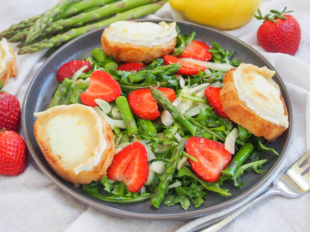 This delicious strawberry asparagus salad brings tasty spring flavors, with a bright lemony dressing and goat cheese toasts on the side (which are optional but go so well). Flavorful and easy to make. plate of strawberry asparagus salad with goat cheese toasts around plate