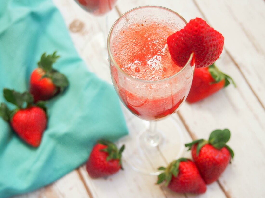 Brighten up your brunch table with this easy strawberry bellini. It takes no time to make and is fresh, colorful and the perfect springtime sip. glass of strawberry bellini with strawberries to side