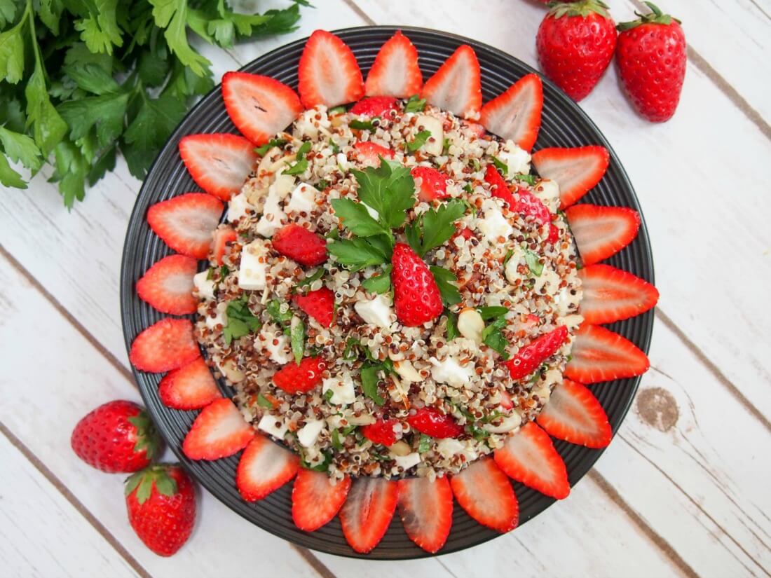 strawberry quinoa salad with feta strawberry quinoa salad with feta on plate with strawberry slices around edge as decoration viewed from above