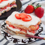 slice of strawberry tiramisu with fork in front and strawberries behind