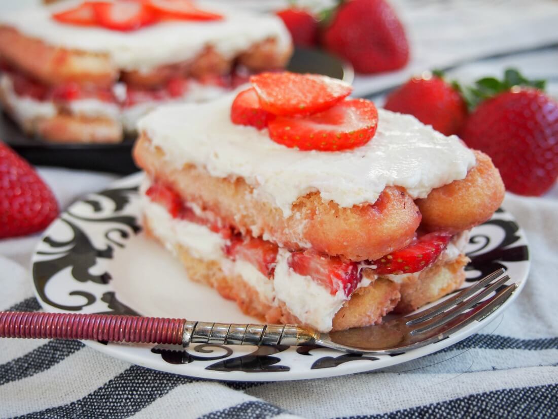 Strawberry tiramisu is a fresh and fruity, family-friendly take on the classic Italian dessert. This version has a double doze of fruit, is a little lighter but super easy and so delicious. piece of strawberry tiramisu on a plate with a fork in front
