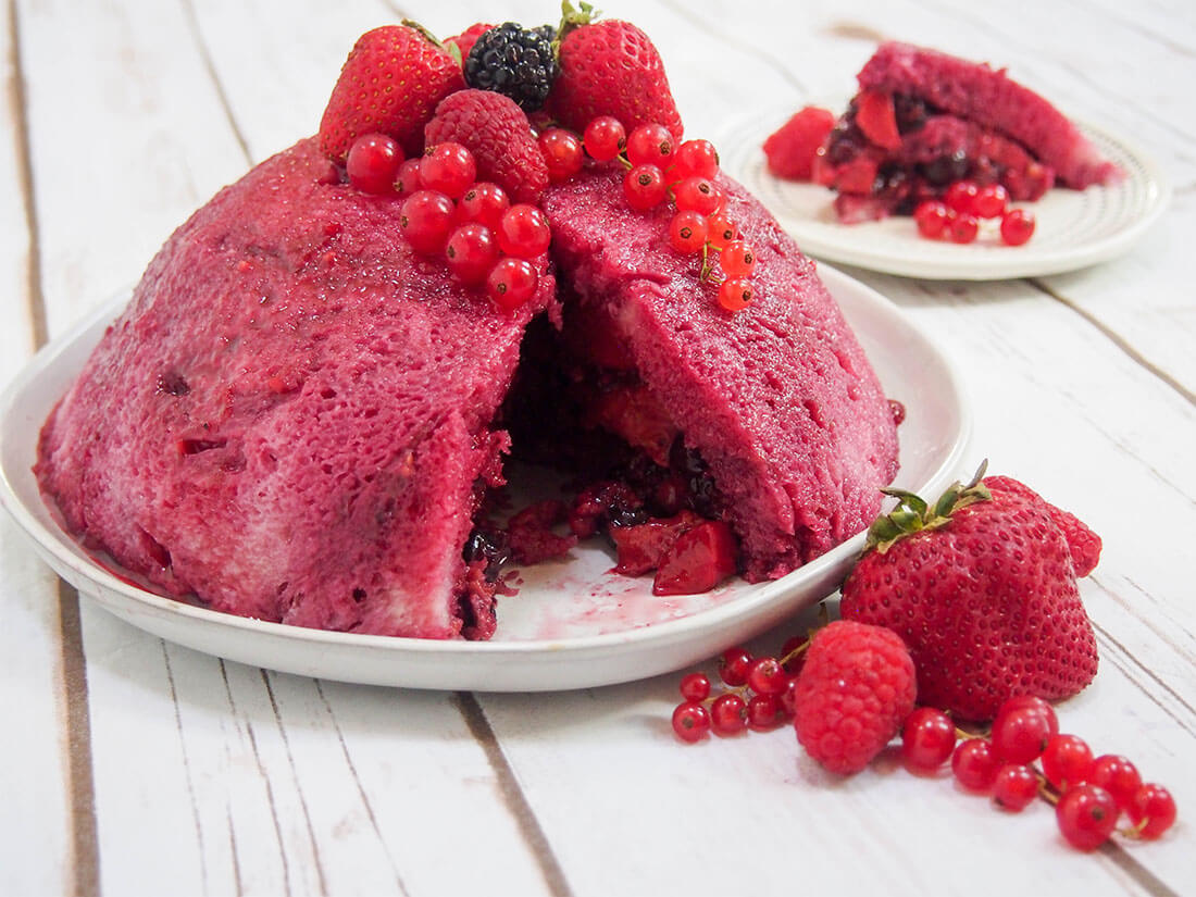 Summer pudding is a classic British dessert - a celebration of summer berries, wrapped up in a sponge-like coat. It's an easy and delicious no bake dessert. summer pudding on plate with berries to side and slice on plate behind