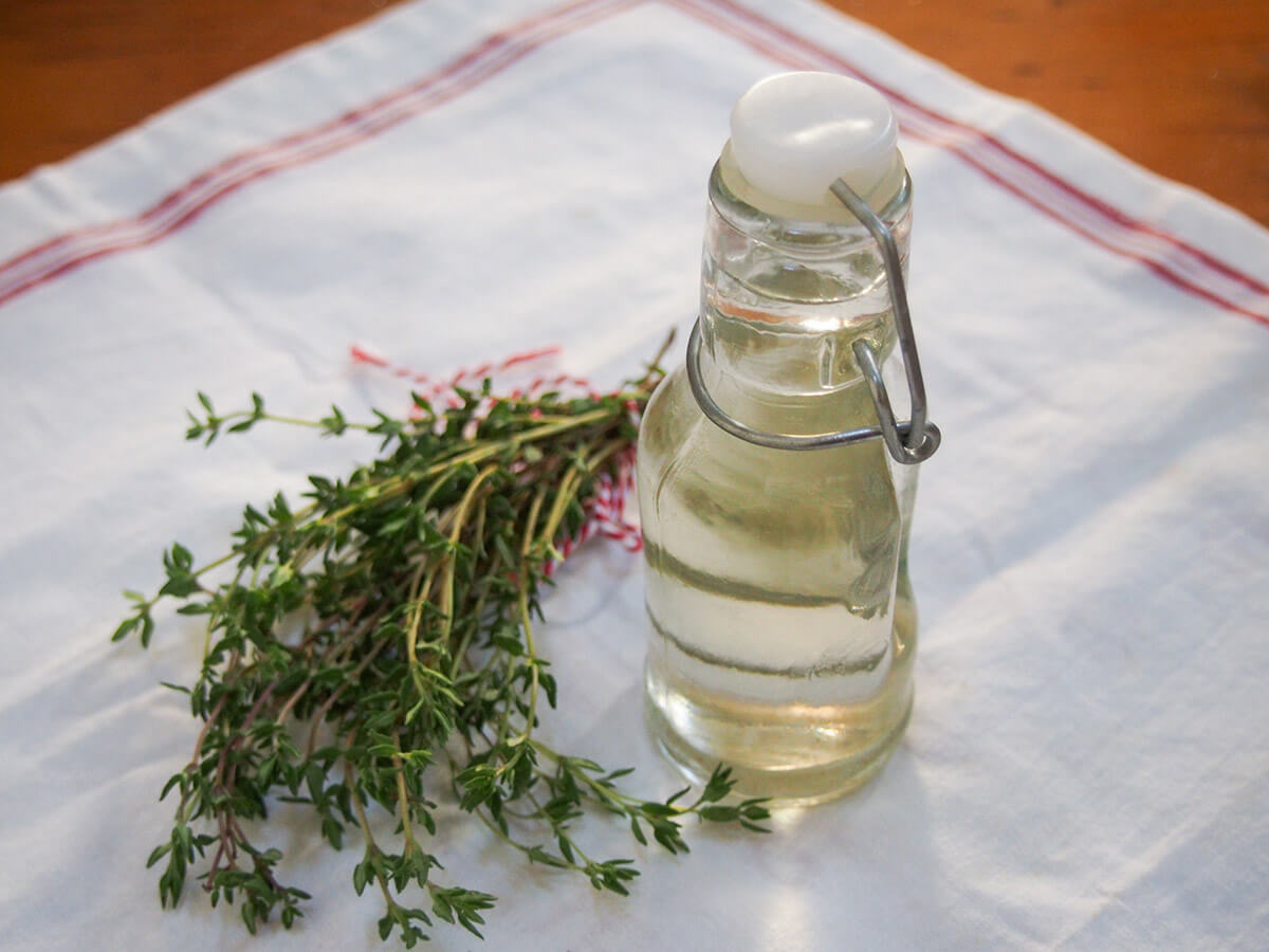 This thyme simple syrup is an easy twist on a plain syrup with a gently aromatic, herbal flavor It's easy to make and adds a lovely flavor to cocktails, lemonade and more. bunch of thyme and bottle of thyme simple syrup next to each other on cloth