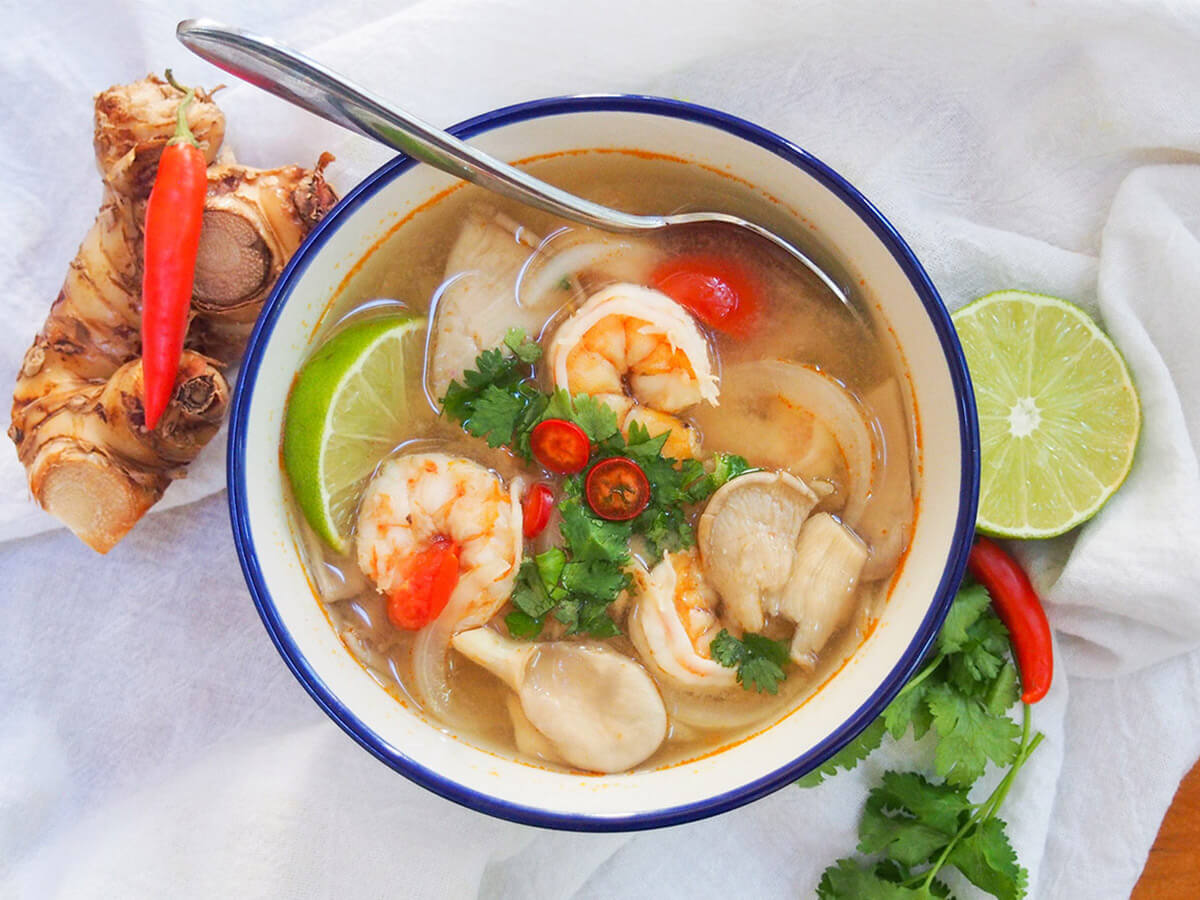 Tom yum soup is a classic Thai soup loaded with wonderful aromatic and spice flavor. It has freshness from lemongrass and lime leaves, and a little chili kick. This favorite shrimp version is easy, comforting and oh so delicious. bowl of tom yum soup with spoon in bowl and spices either side of bowl
