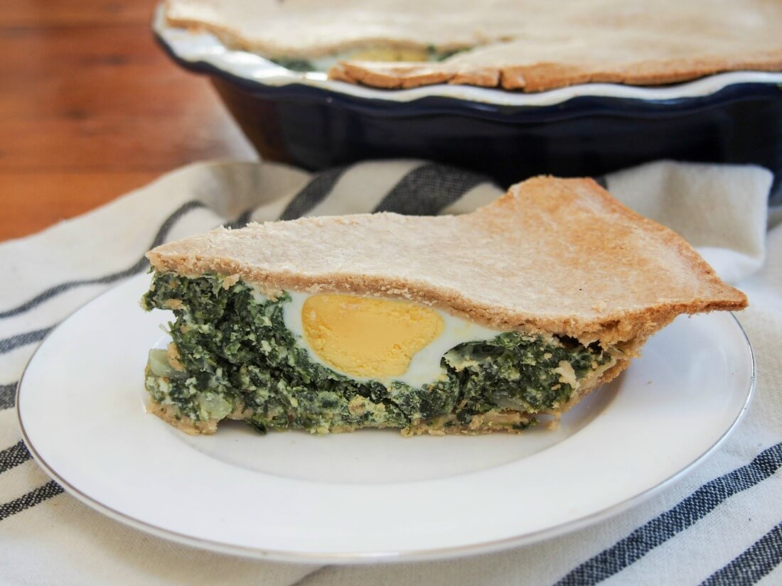 Torta pascualina is originally an Italian pie common in Argentina and Uraguay as a popular Easter dish. Whenever you serve this, it's a delicious combination of cheeses, spinach and egg, wrapped up in crisp pastry. Great for brunch/lunch. slice of torta pascualina spinach ricotta pie showing egg inside