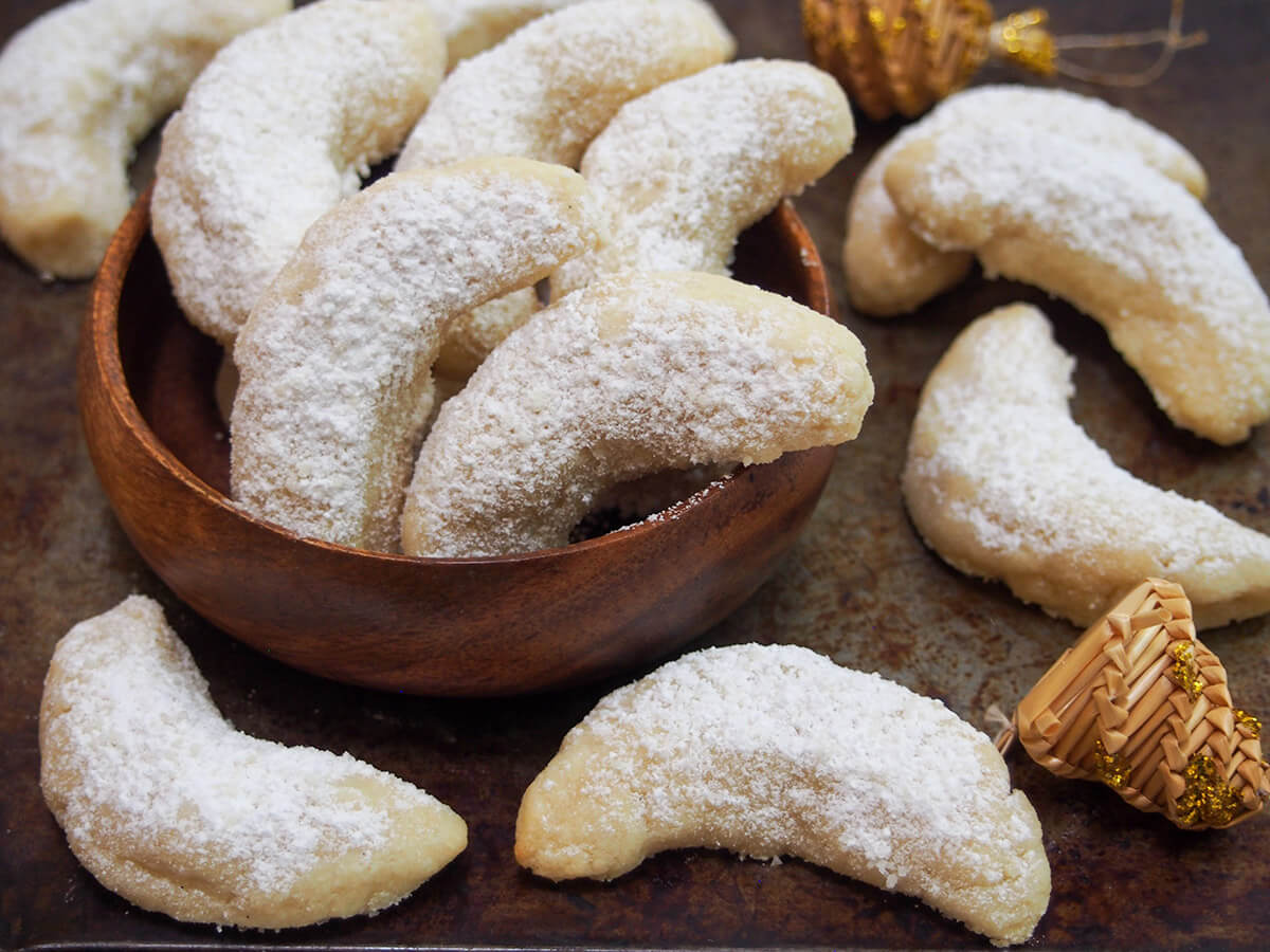 Vanillekipferl (vanilla crescent cookies) are a classic Austrian/German cookie with a delicate vanilla flavor. They melt in your mouth and are a perfect addition to a seasonal cookie plate. vanillekipferl vanilla crescent cookies in small dish