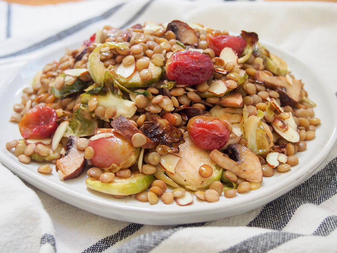 This vegan lentil salad combines earthy lentils with flavorful roasted Brussels sprouts, mushrooms and grapes. It's incredibly easy to make and so versatile in how you enjoy it. plate of lentil salad from side