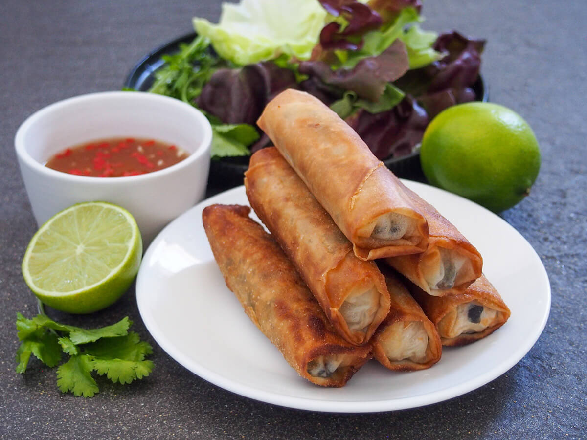 Vietnamese fried spring rolls (cha gio) have a delicious mix of crisp outside and tasty filling which includes noodles and pork. They make a great appetizer dipped in light nuoc cham sauce or added to other dishes. plate of Vietnamese fried spring rolls with nuam choc and limes to side