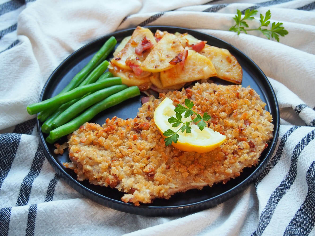 This authentic Wiener schnitzel recipe, aka breaded veal cutlets, is a great main for any night. It's practically the national dish of Austria and for good reason - it's easy to make, child friendly & delicious. Wiener schnitzel on plate with potatoes and beans