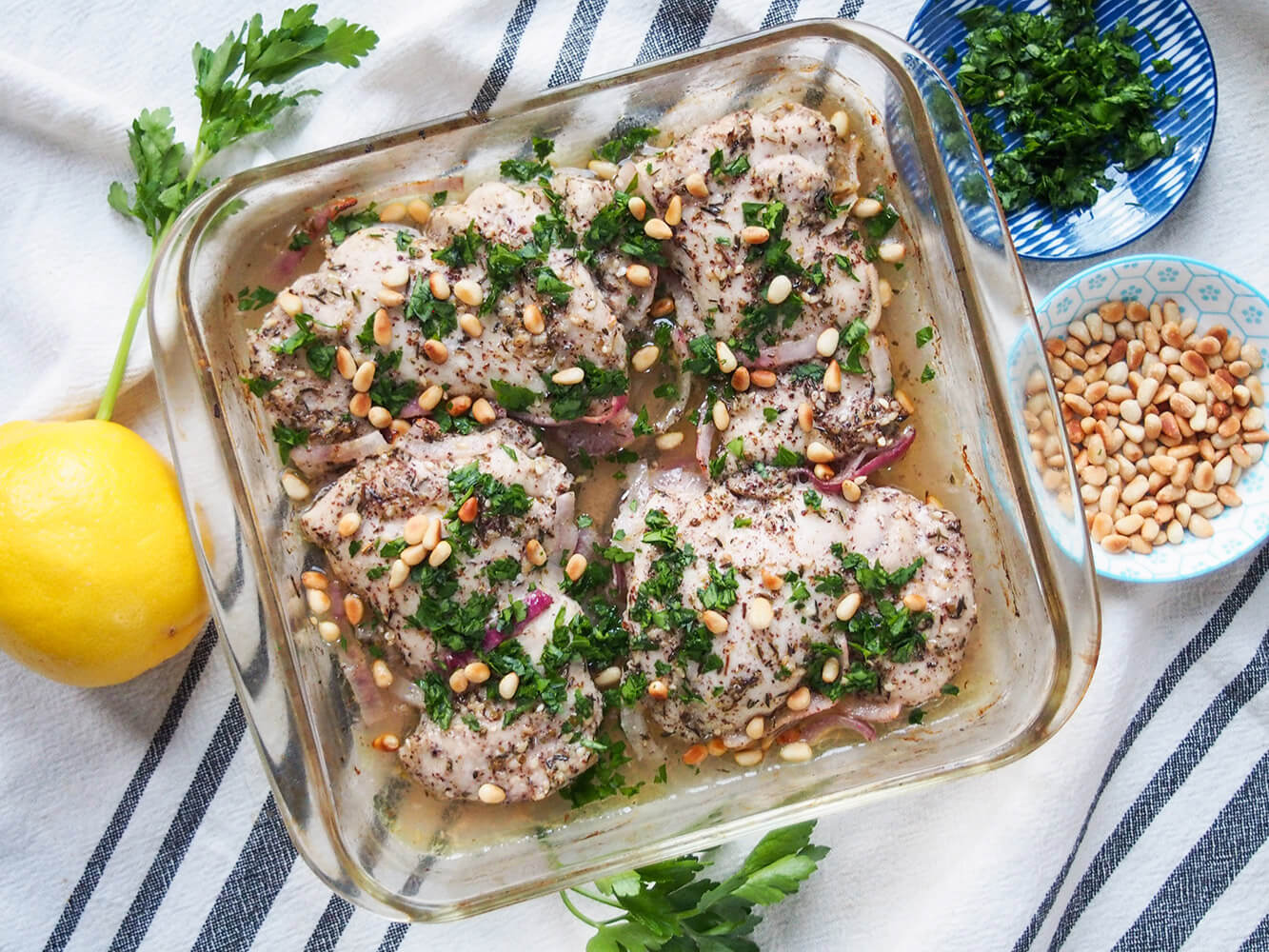 This za'atar/ zaatar chicken is easy to make, wonderfully moist and the flavors are gentle but fragrant. baking dish with za'atar chicken with lemon, parsley and pine nuts to side